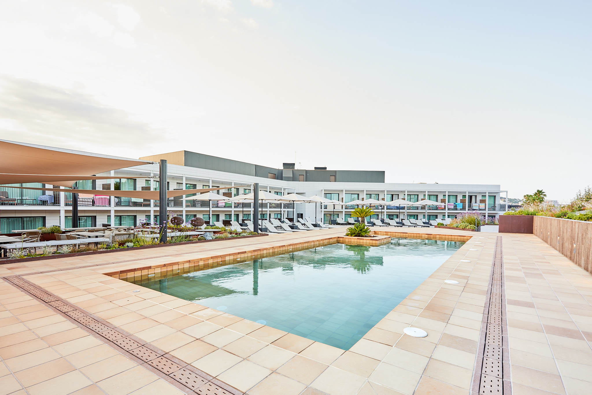Terrasse mit Schwimmbad und leeren Liegestühlen.