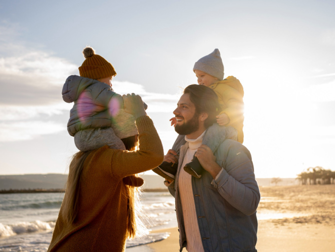 Familia jugando en la playa al atardecer.
