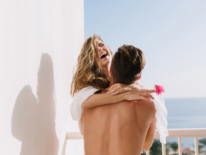 Pareja abrazándose y sonriendo al aire libre.