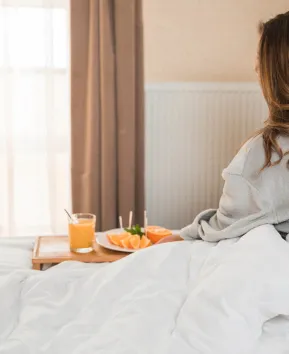 Mujer con un desayuno en la cama.