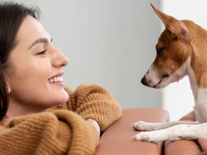 Femme souriante face à un chien.