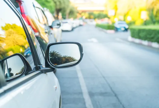 Car mirror reflecting palm trees.