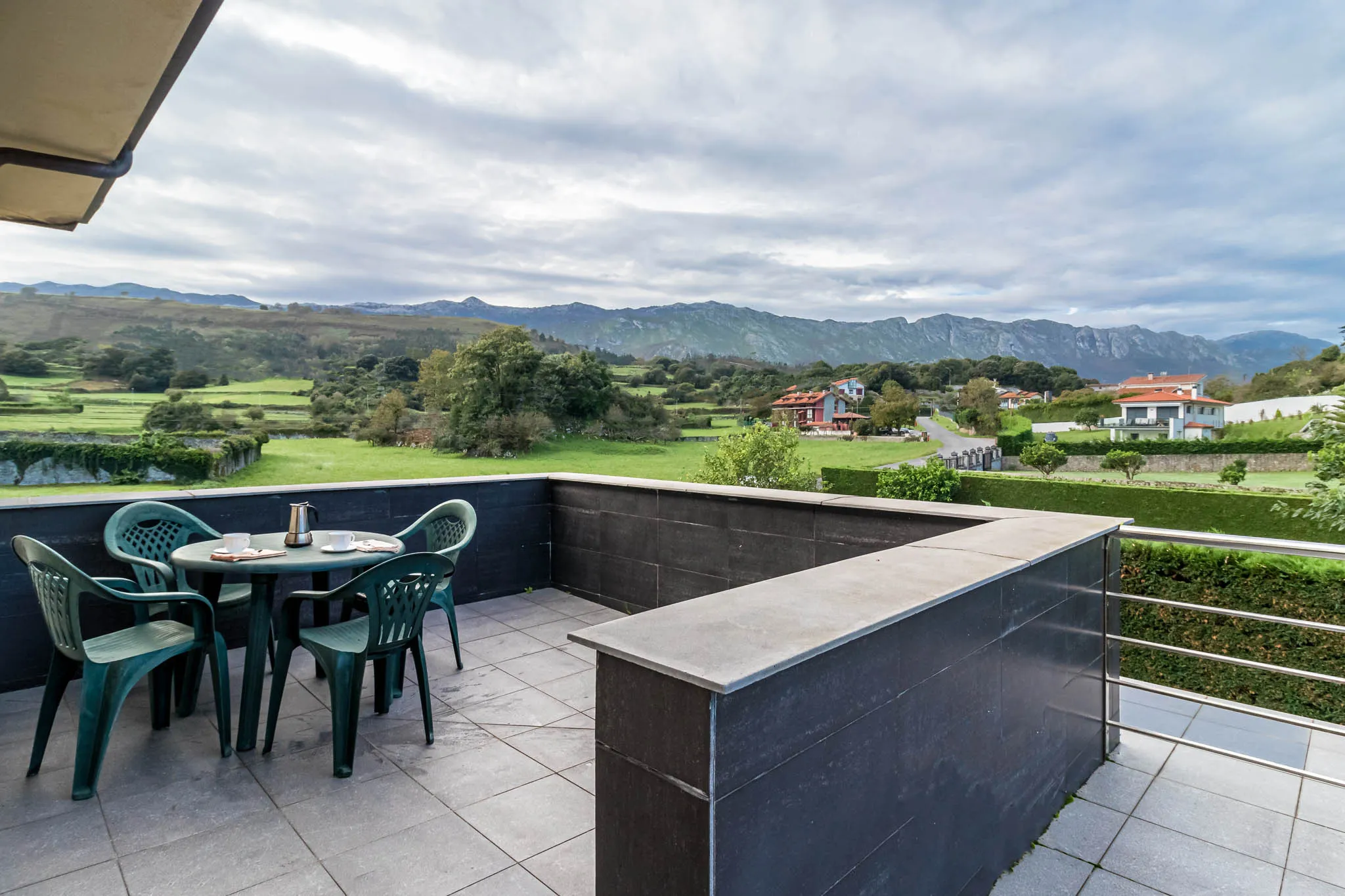 Terrace with table, chairs, and landscape.