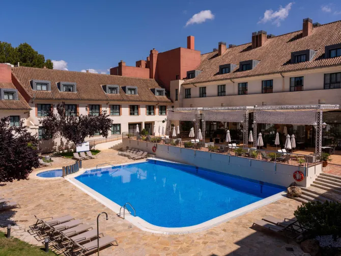 Piscine d'hôtel avec terrasse ensoleillée.