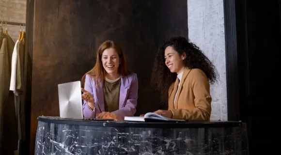 Two women smiling in front of a laptop.