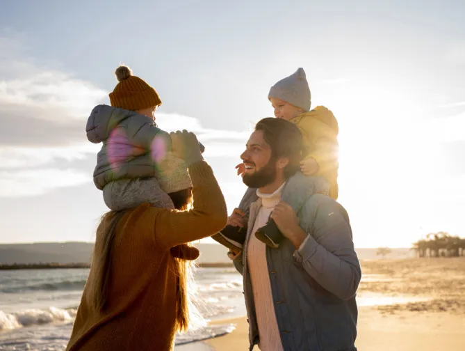 Famille jouant sur la plage au coucher du soleil.