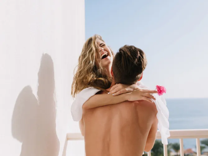 Couple s'enlaçant et souriant en plein air.