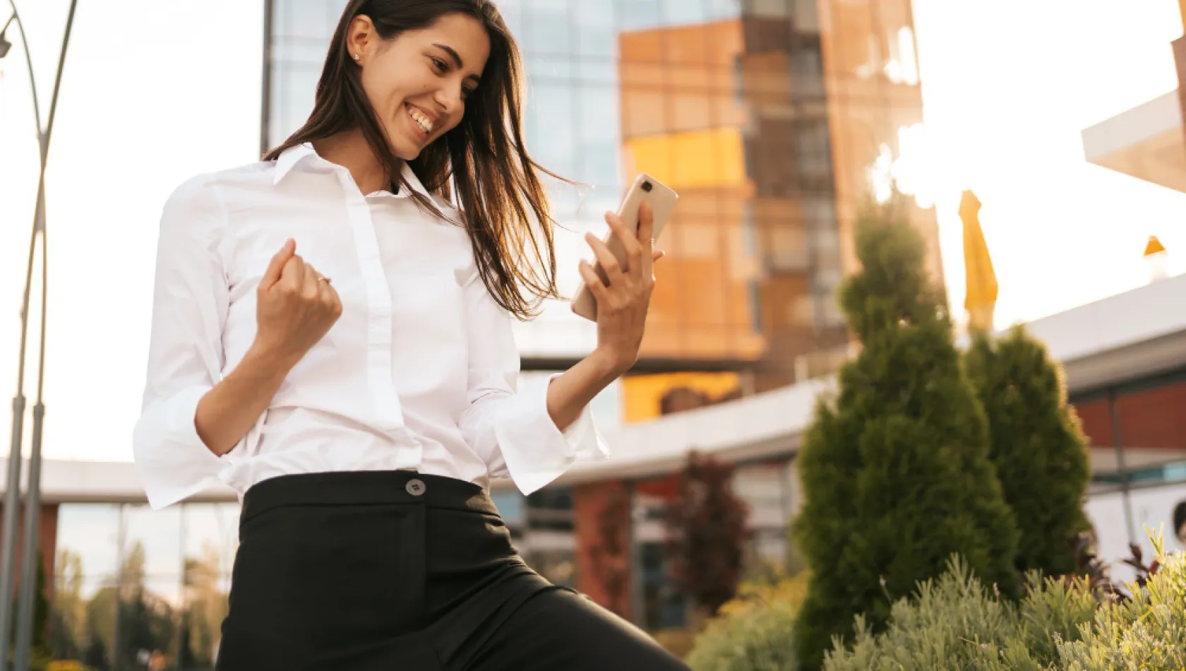 Femme souriante avec un téléphone en plein air.